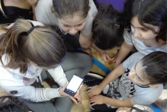 Mädchen hören gespannt die Radiosequenz über das Smartphone